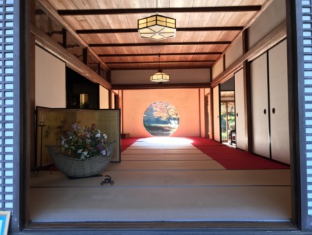 Circular window in the main hall(Hojo) with autumn leaves at Meigetsuin in Kamakura